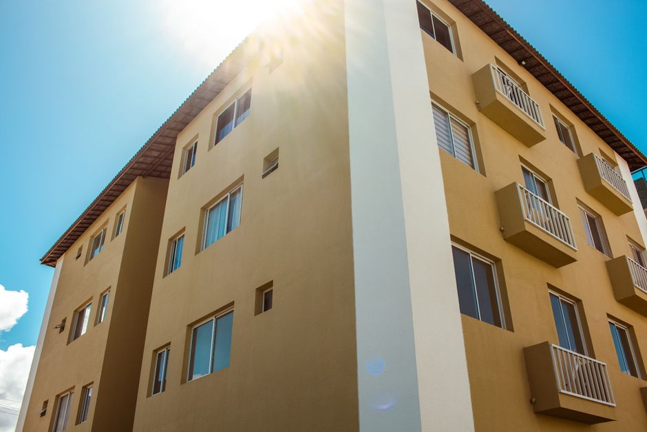 Um edifício de apartamentos moderno recém-construído com varandas e janelas sob a luz solar brilhante.